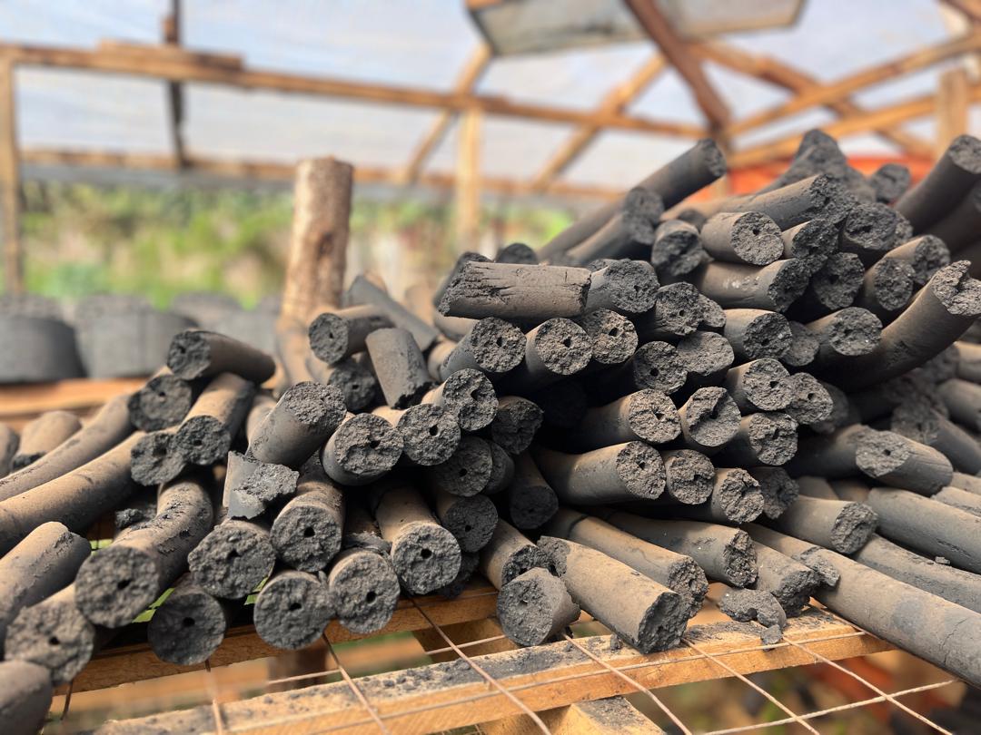Green Flame stick briquettes — cylindrical compressed biomass rods with central air-channels on drying racks