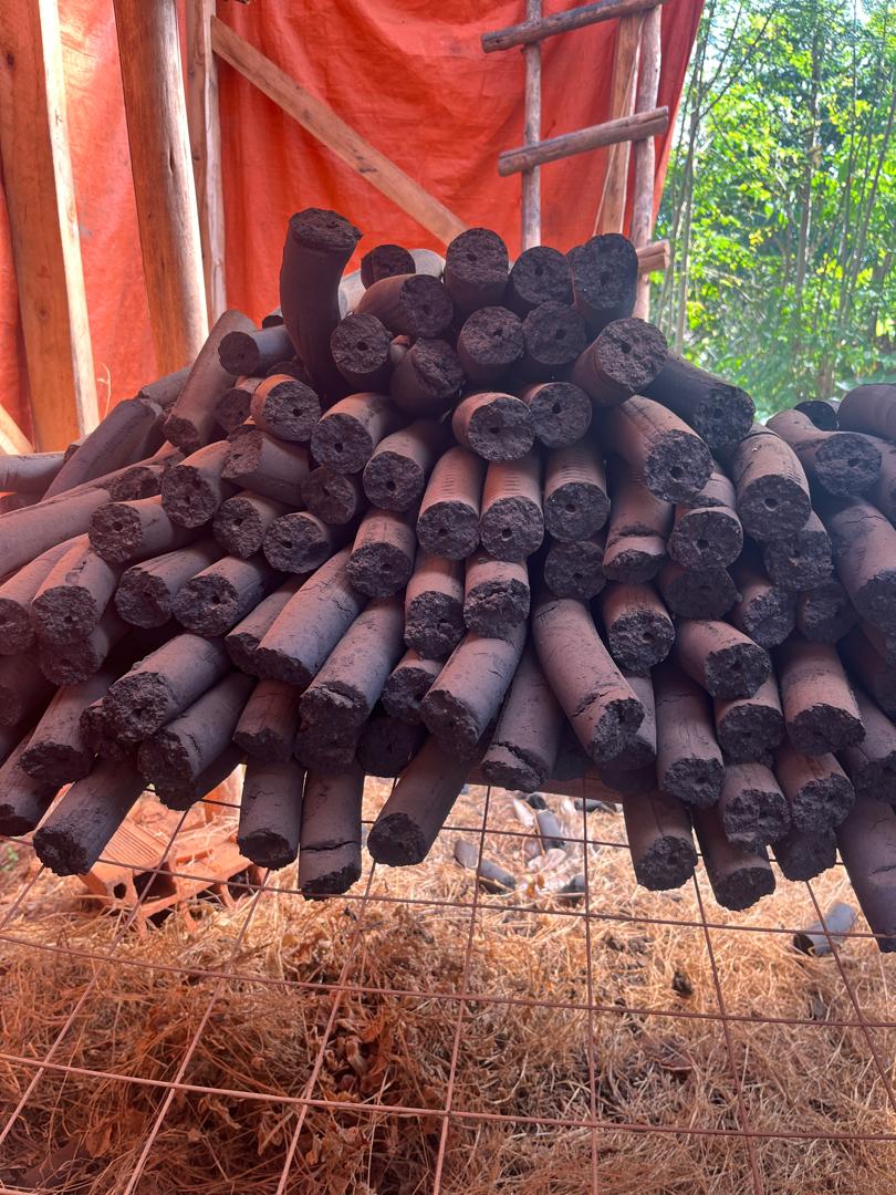Stick briquettes stacked on wire mesh at outdoor production area